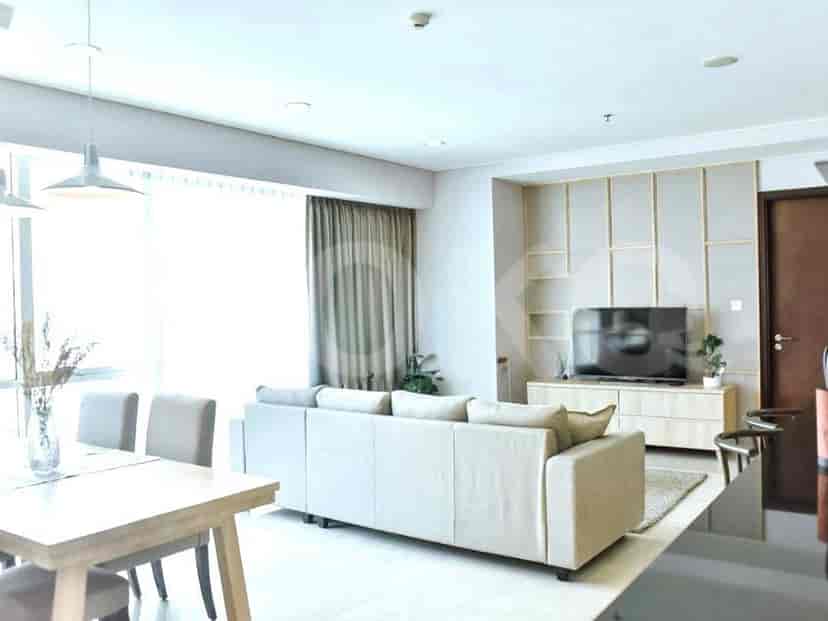Living room with a grey sofa, TV, and dining area adjacent to the kitchen.