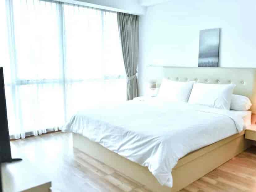 A bedroom with a bed, large windows, and curtains.
