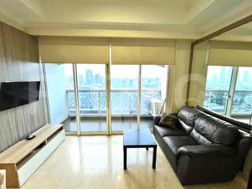 Ruang tamu modern yang menampilkan sofa kulit hitam, TV yang dipasang di dinding, dan jendela besar dengan pemandangan kota.
