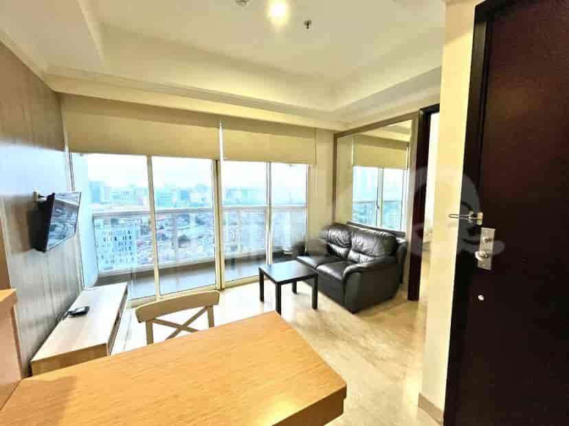 Ruang tamu dengan sofa, meja, TV, dan area makan dengan pemandangan kota.