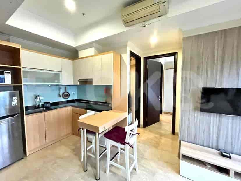 Dapur terbuka modern dengan lemari berwarna terang dan meja makan kecil.