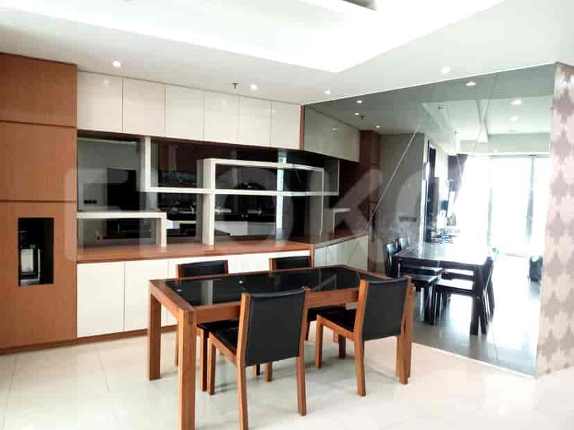 Dining area with a dark wood table and chairs next to a mirror wall.