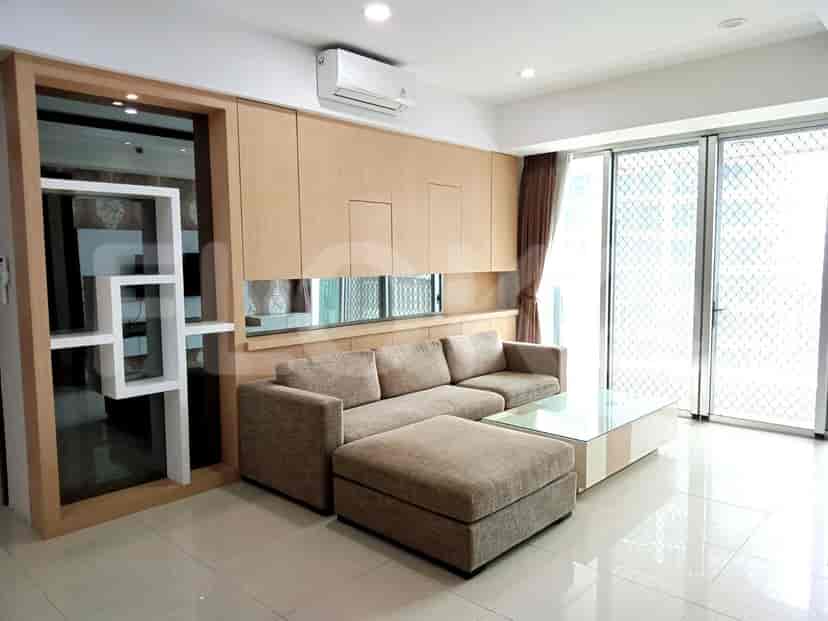 Living room with beige sofa, glass coffee table, and built-in cabinetry.