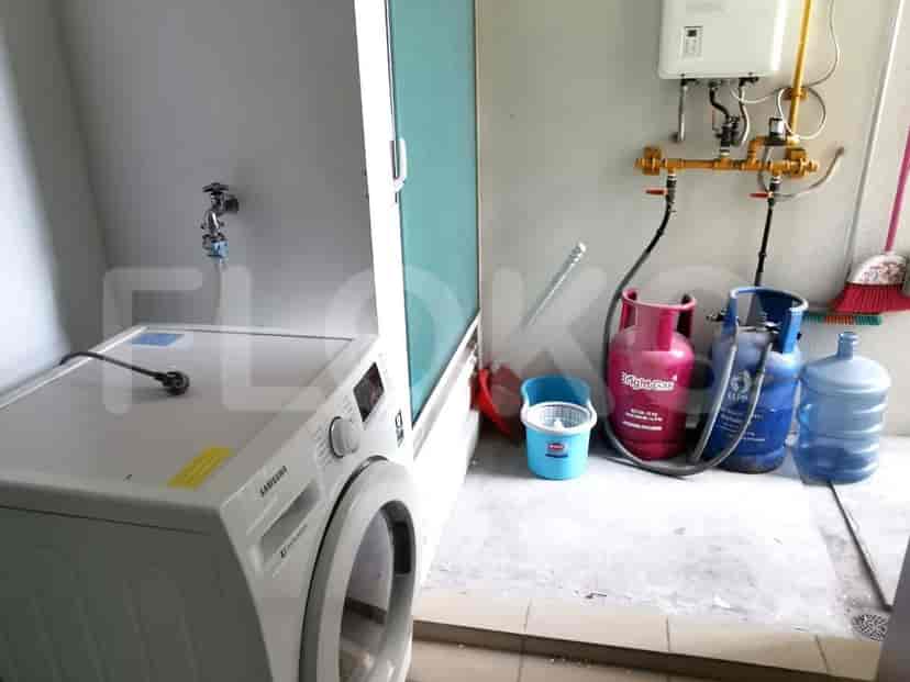 Mesin cuci dan tabung gas di area binatu.