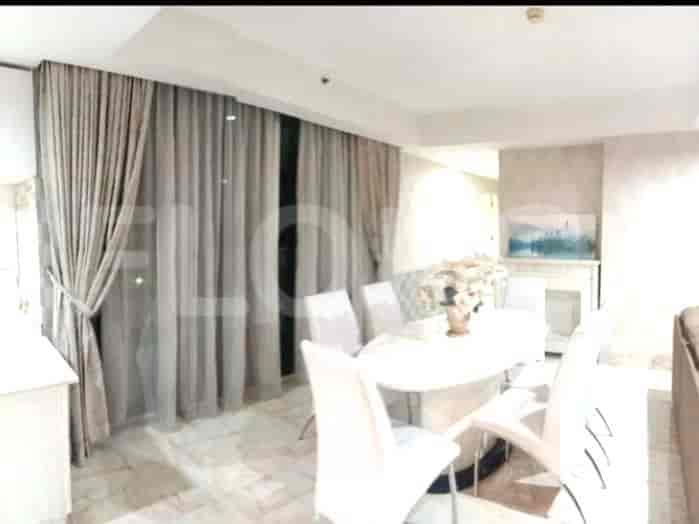 Elegant dining area with a large oval table, white chairs, and window with drapes.