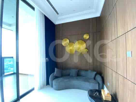 A modern living room with a grey curved sofa, decorative wall art, and floor-to-ceiling windows.