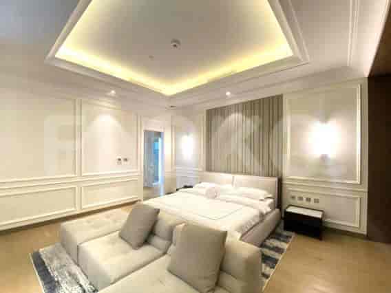 A luxurious bedroom with a king-sized bed, a large sofa bench, and recessed ceiling lighting.