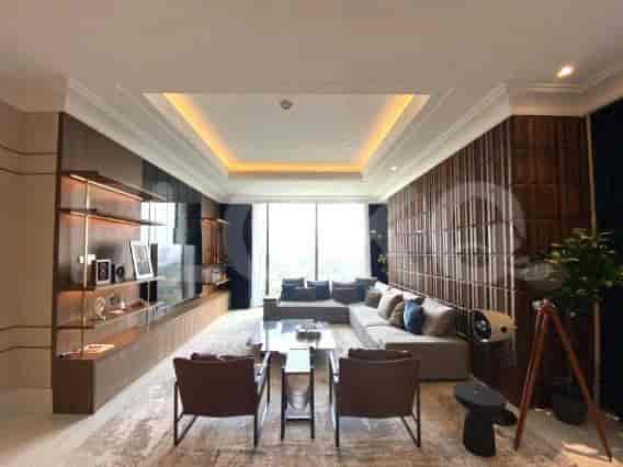 A spacious living room with a large L-shaped sofa, a TV, and built-in shelves.