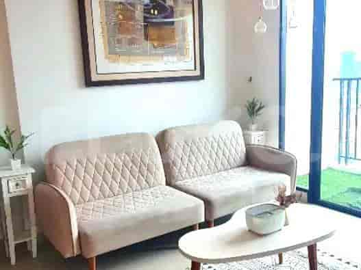 Ruang tamu dengan dua sofa krem, meja kopi, dan karya seni berbingkai.