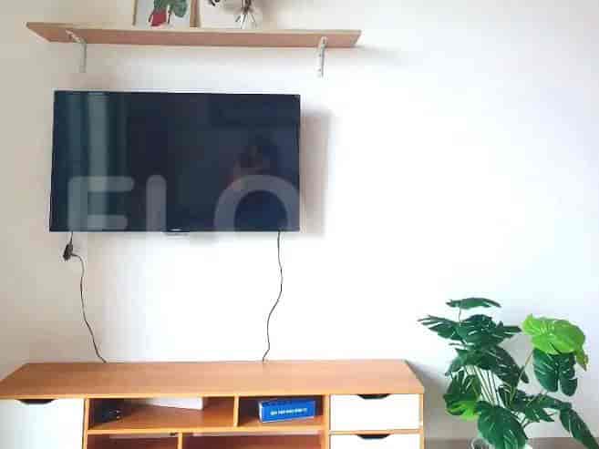 Ruang tamu dengan TV, konsol, dan barang-barang dekoratif.