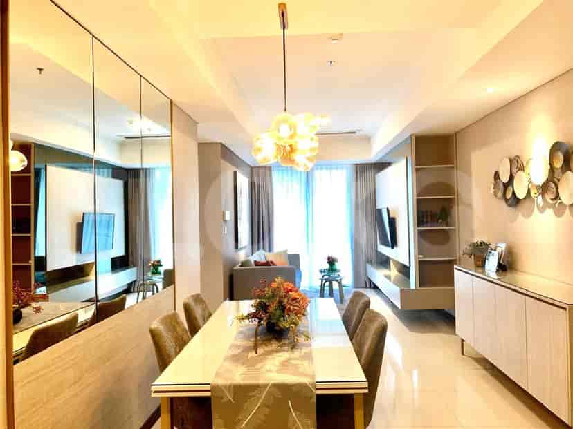 Area makan dengan meja makan panjang, dan tata letak ruang tamu dengan sofa dan TV.