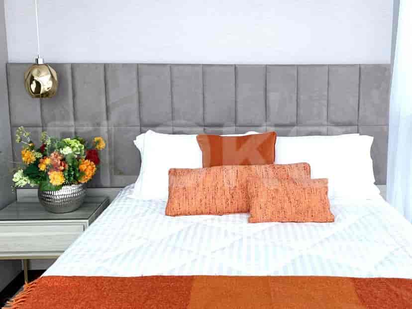 Kamar tidur dengan tempat tidur ukuran queen, meja samping tempat tidur, dan pot bunga dekoratif.