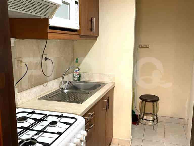 Kitchenette with sink, stove, microwave, and stool.