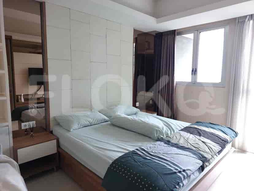 A well-lit bedroom featuring a bed with light blue bedding, large mirrors, and a window with curtains.