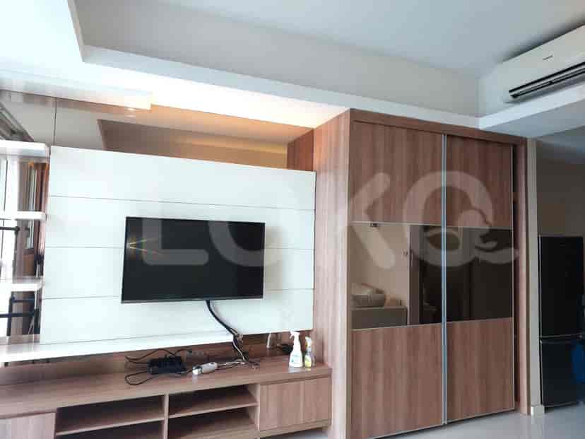 A living room featuring a wall-mounted TV, a wooden wardrobe, and a clean modern design.
