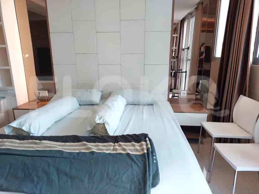 A well-lit bedroom with a bed with light blue bedding, large mirrors, and a window with curtains.