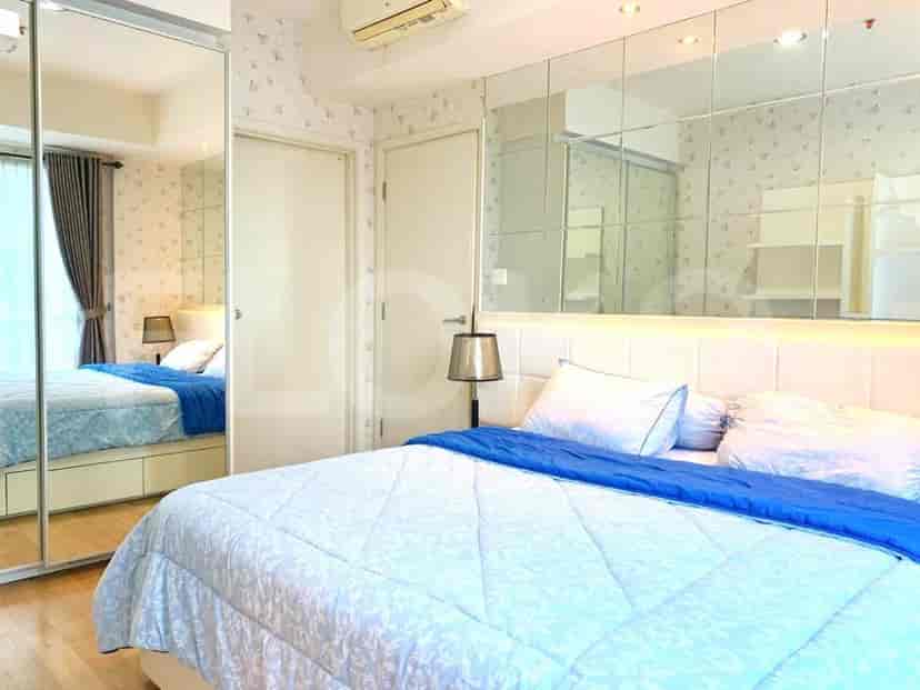 A well-lit bedroom with a large bed, mirrored wall, and a touch of blue.