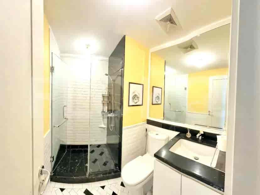 Kamar mandi modern dengan pancuran walk-in dan wastafel.