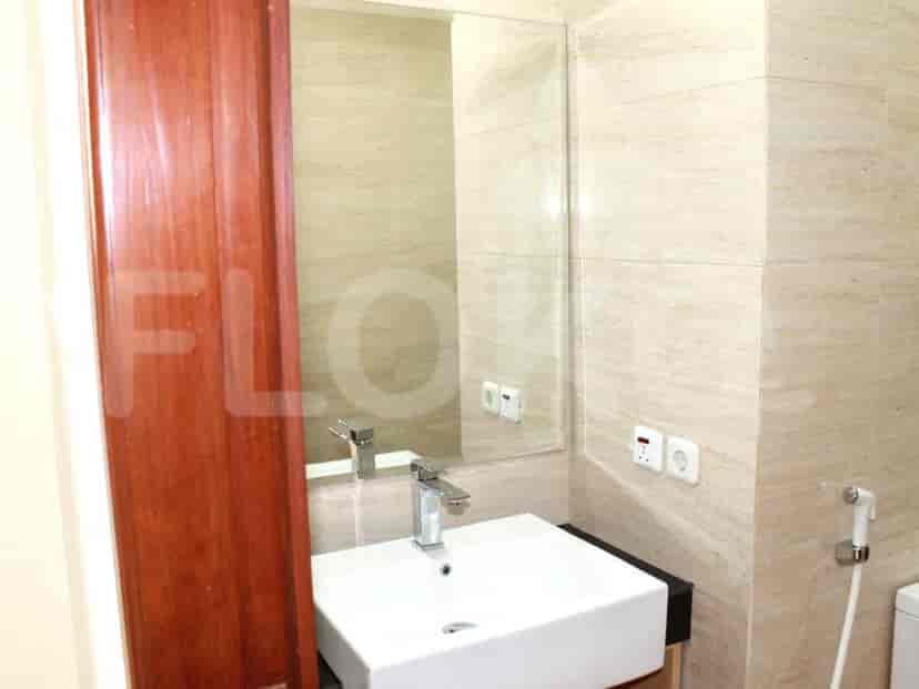 A small bathroom with a white sink, mirror, and tiled walls.