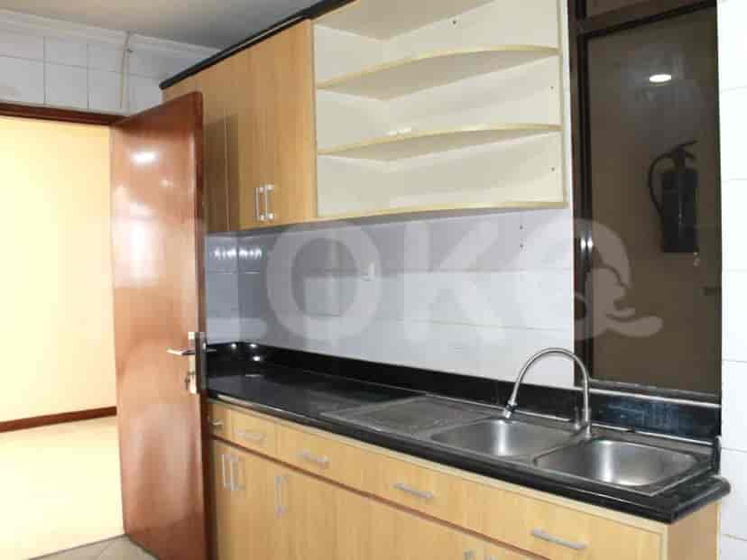 A kitchen with wooden cabinets, stainless steel sink, and a black countertop.