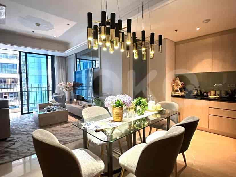 Dining area with glass table, chairs, and modern chandelier; adjacent to a minimalist kitchen.