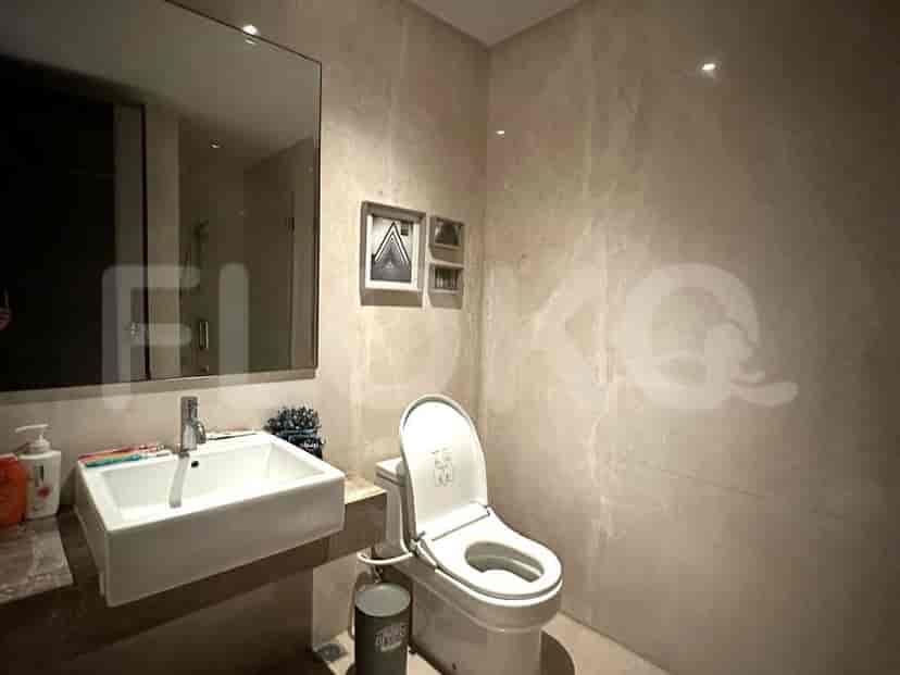 Bathroom with a toilet, sink, and marble walls.