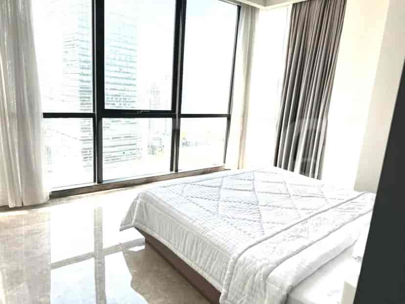 A bright bedroom with a queen bed, large windows, and sheer curtains.