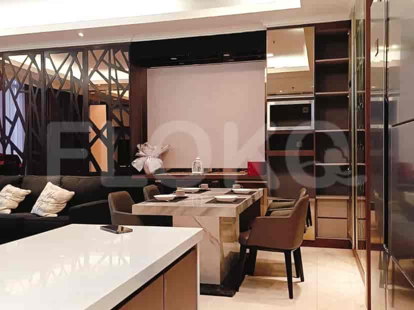 Area ruang tamu dan ruang makan modern dengan meja makan, sofa gelap, dan penyimpanan built-in.