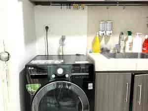 A small laundry area with a washing machine and overhead storage.