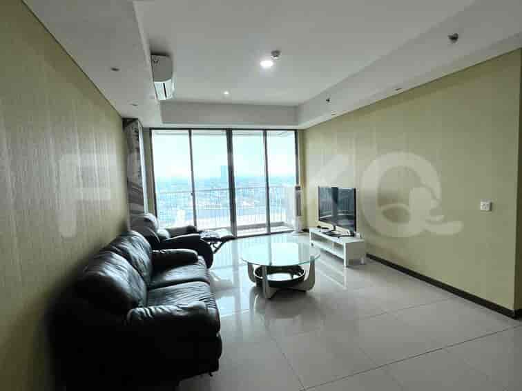 A modern living room with a black leather sofa, glass coffee table, and a view of the city.