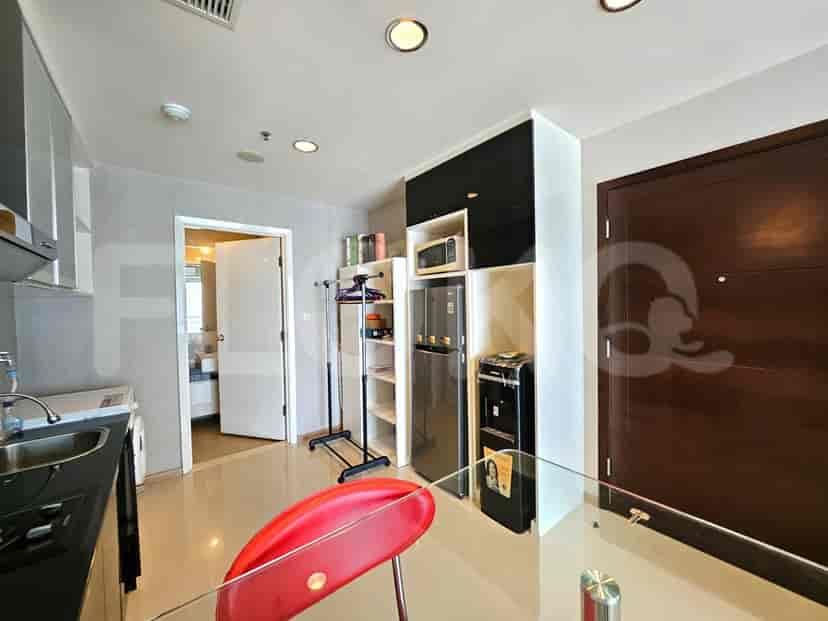 Compact kitchen area with a refrigerator, microwave, sink, and a small dining table with a red chair.