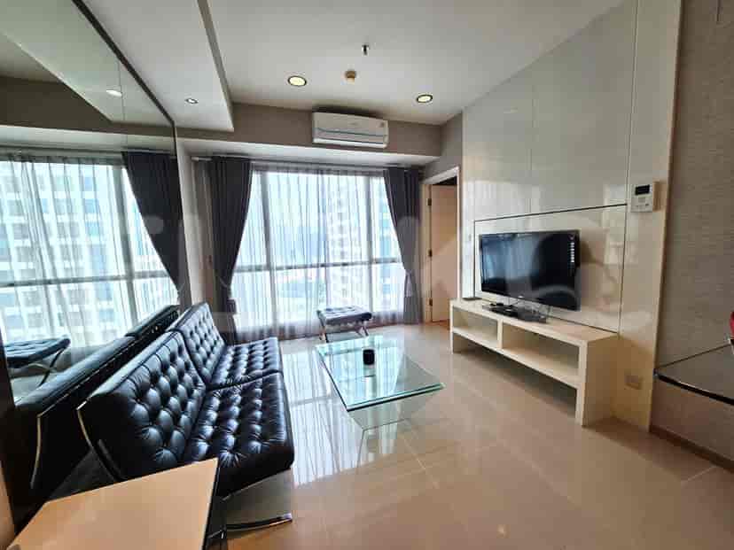 Modern living room with a black tufted sofa, glass coffee table, and large windows with city views.
