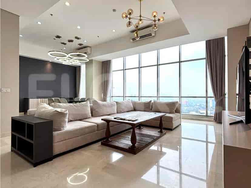 A spacious living room with a large sectional sofa, a coffee table, and floor-to-ceiling windows offering a city view.