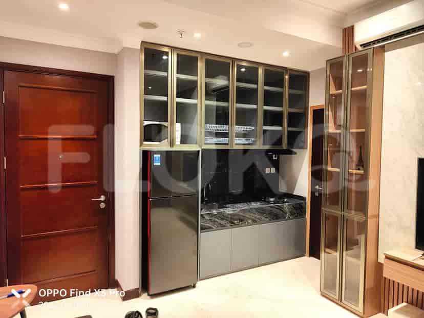 A compact kitchen with stainless steel appliances, built-in cabinets, and a marble countertop.