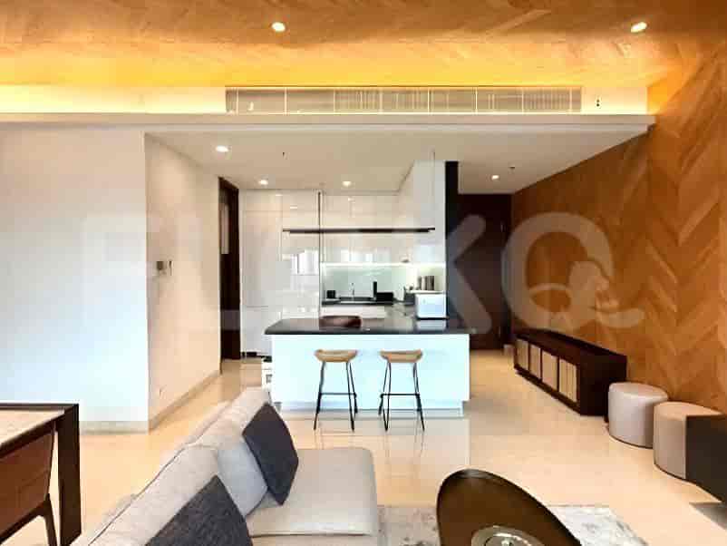 A modern open-plan kitchen with white cabinetry, a black countertop, and stainless steel appliances.
