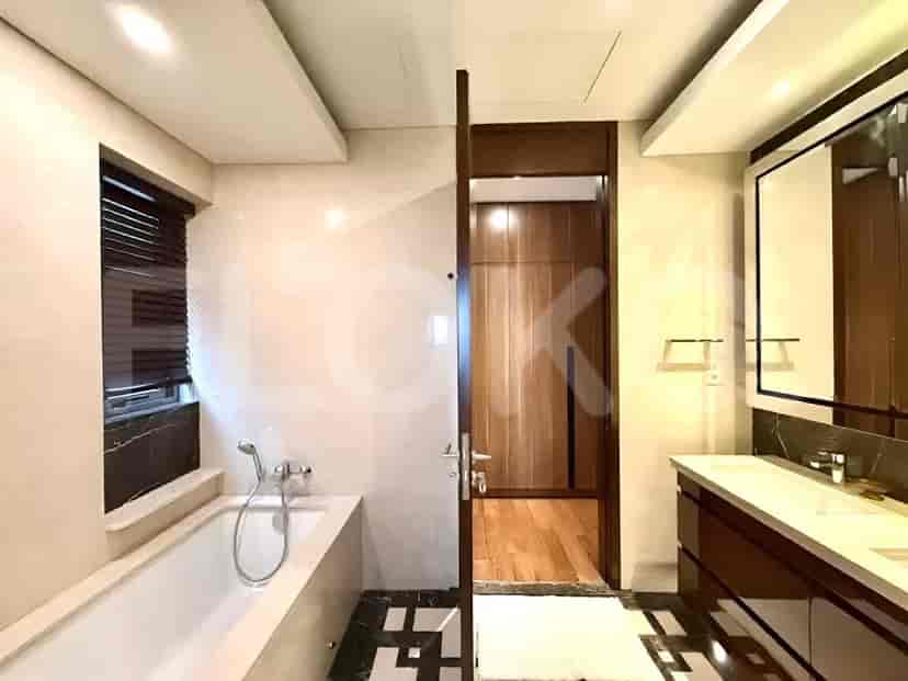 A bathroom featuring a bathtub, a dual vanity, and a wooden door leading to a closet area.