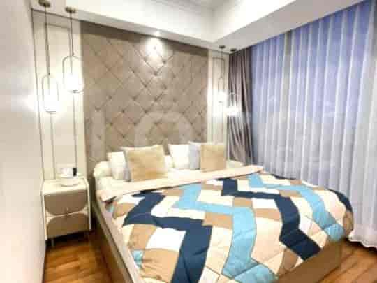 A bedroom with a large bed, a padded headboard, and pendant lights.