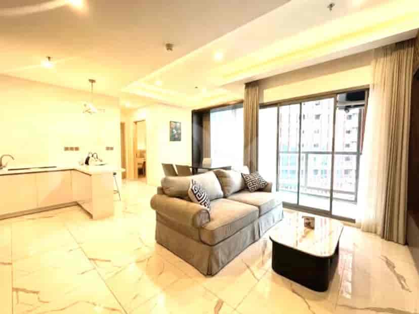 A modern living room with a grey sofa, coffee table, and an open-plan kitchen in the background.