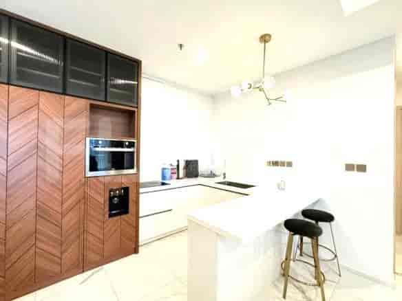 A modern kitchen with built-in appliances, white countertops, and wood cabinetry.