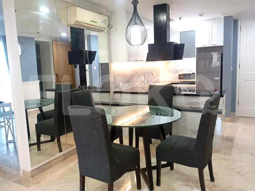 An open-plan kitchen and dining area with a glass-top dining table, chairs, and modern kitchen appliances.