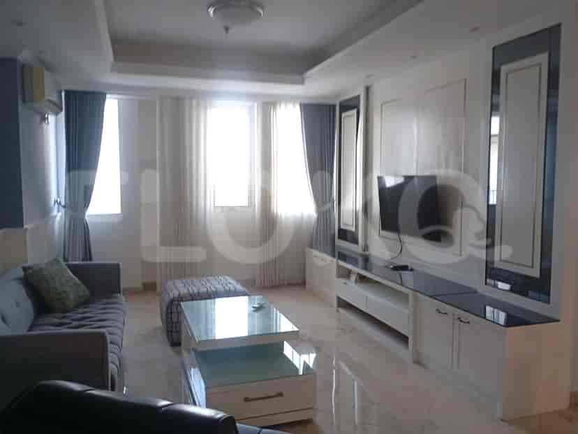 A modern living room with a grey sofa, ottoman, coffee table, and a wall-mounted TV.