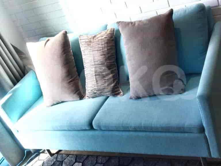 Sofa biru dengan tiga bantal dekoratif.
