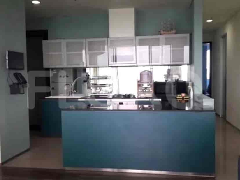 A modern kitchen with teal cabinets and a white countertop, featuring ample storage and appliances.