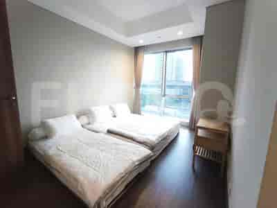 A bedroom with two single beds, a nightstand, and a window overlooking a cityscape.