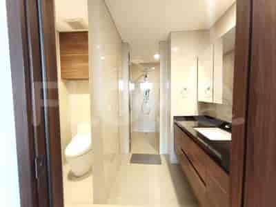 A bathroom with a toilet, a vanity with a sink, and wooden cabinets.