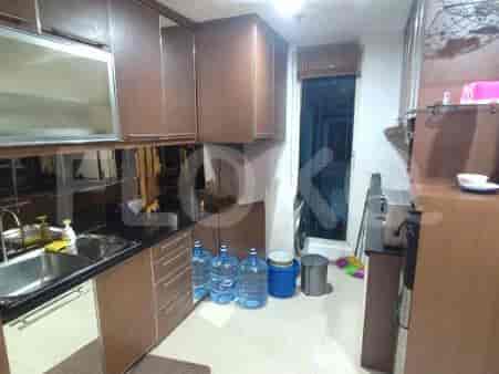 Dapur ringkas dengan kabinet kayu gelap, wastafel stainless steel, dan meja dapur hitam.