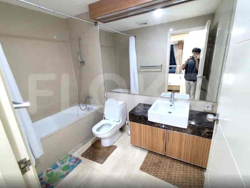 Kamar mandi modern dengan bak mandi, toilet, dan vanity dengan wastafel di atas meja.