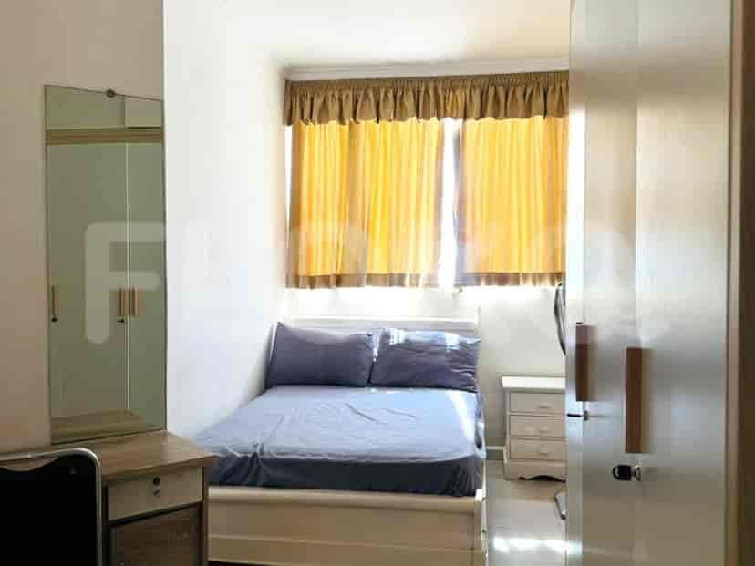 A bedroom with a single bed, nightstand, wardrobe, and a window with yellow curtains.