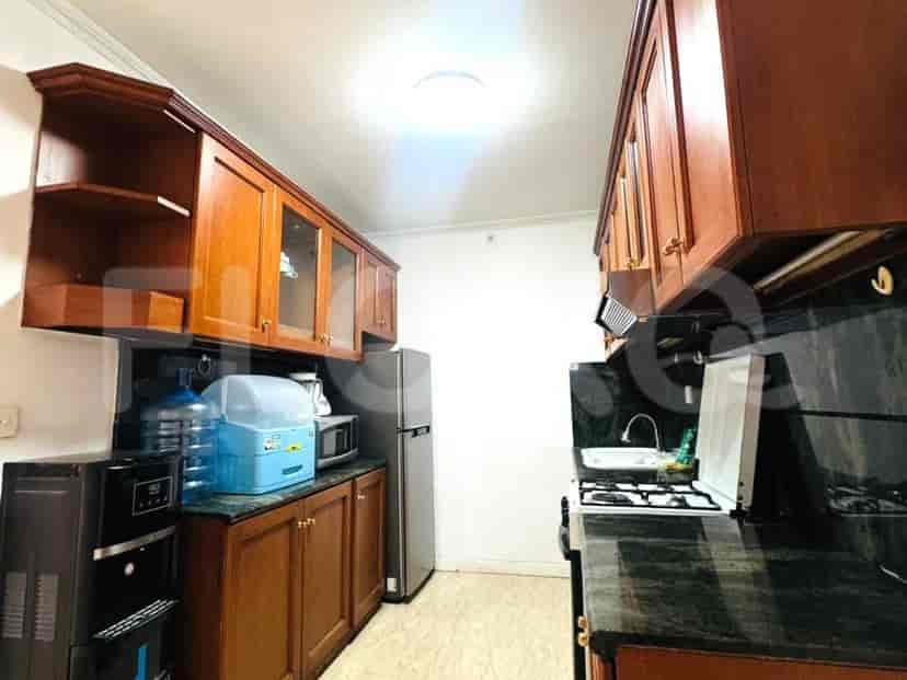 A kitchen with wooden cabinets, granite countertops, refrigerator, microwave, and a water dispenser.