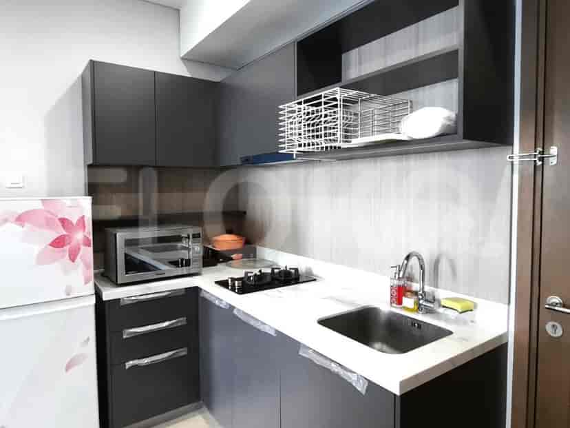 Dapur ringkas dengan lemari abu-abu gelap, kompor, microwave, dan kulkas.